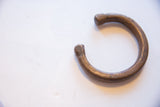 C-shaped antique bronze cuff bracelet showing the detailed markings and aged patina on the ends.