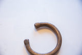 Simple etched markings on the smooth, worn terminal of the bronze snake cuff.
