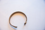 Profile view of the antique bronze cuff showing its open, curved shape.