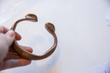 View of the antique bronze snake cuff's open, curved form.