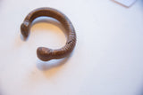 Side view of the antique copper snake cuff showing its ribbed texture and storied patina.