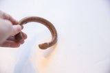 Antique copper snake cuff held to display its outer curve and carved texture.