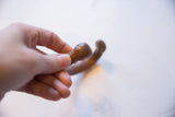 A hand holding the smooth, rounded copper head of the antique snake bracelet.