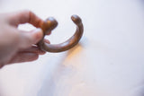 Antique copper alloy snake cuff bracelet held to show its curved shape and scale.