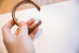 Antique copper alloy snake cuff bracelet held, showing its curved form and warm patina.