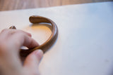 Profile view of the antique copper snake cuff's smooth, curved form.