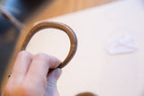 Curved form of an antique copper snake cuff highlighting its rich patina and etched lines.