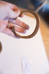 A hand holding the antique copper cuff bracelet to show its open form and scale.