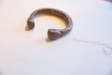 Aged patina and stamped details on the terminal of an antique African copper cuff.