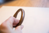 The solid, curved body and aged patina of the antique copper cuff.