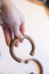 Antique copper alloy cuff bracelet held to show its substantial form and scale.