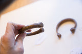 Antique African copper bracelet held in hand showing its scale and terminal detail.