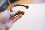 Hand holding the antique copper snake cuff showing its ribbed body and form.