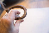Antique African copper alloy cuff held in hand to show its scale and curved form.