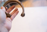 Profile view of an antique African copper cuff, showing its C-shape and etched terminals.