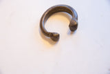 Antique African bronze snake cuff bracelet showing its heavy form and aged patina.