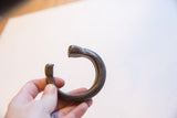 Antique bronze snake cuff held to show its scale and open C-shape design.
