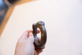 Antique African bronze cuff bracelet held in hand, showing its substantial form and scale.