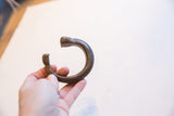 Hand holding the antique bronze snake cuff, showing its curved form and opening.
