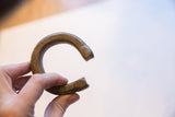 Antique African bronze snake cuff bracelet showing its C-shape profile and etched snake heads.