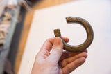 Antique African bronze snake cuff held to demonstrate its size and form.