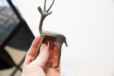 Right-facing vintage African gazelle figurine, dark metal patina, held in hand.