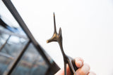Profile view of the vintage gazelle's stylized head showing its dark, patinated finish.