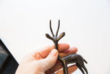 A hand holding the vintage African gazelle figurine, showing its scale and slender antlers.