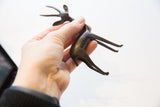 Vintage African gazelle figurine held in hand to illustrate its scale and dark finish.