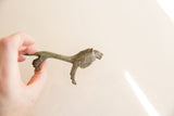 Vintage oxidized African lion held by the tail to demonstrate its slender size.
