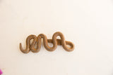 The textured, rusted surface of the vintage African iron snake figure.