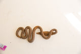 Collectible vintage African iron snake with a rough, rusted surface and coiled form.
