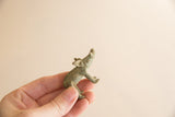 Profile view of the patinated bronze boar held to demonstrate its small scale.