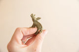 A hand holding a small, textured vintage bronze boar figurine from the side.