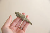 Vintage pangolin sculpture held in hand to demonstrate its small size and scaled texture.