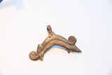 The hand-cast texture and hanging loop of the vintage African pendant.