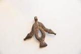 The sculptural, abstract form of a vintage African pendant with a dark, aged patina.