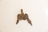 The back of a vintage African pendant with a coarse, dark brown texture.