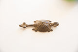 Stylized animal form and aged dark bronze texture on a vintage African pendant.