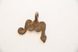 Reverse view of a vintage African pendant showing its aged, textured metal surface.