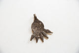 Back of the vintage African pendant with a dark, textured metal patina.