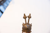 The sculptural twin-headed top of a vintage African pendant showing aged texture.