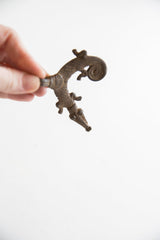Vintage African pendant held to show its aged texture and reptilian form.
