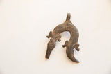 Textured dark metal and weathered patina of a vintage African pendant with two animal figures.