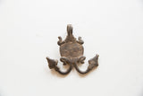 The dark, aged patina on the reverse side of a vintage African metal pendant.