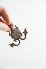The aged, textured metal and sculptural form of a vintage African pendant.