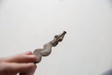 Vintage African pendant held to show a detailed view of its carved head.