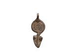 Vintage African pendant with an incised spiral design and weathered metal patina.