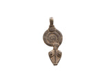 Vintage African pendant with a dark aged patina, featuring an engraved spiral and stylized face.