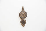 A spiral and arrow-shaped vintage African pendant with a dark, earthy patina.